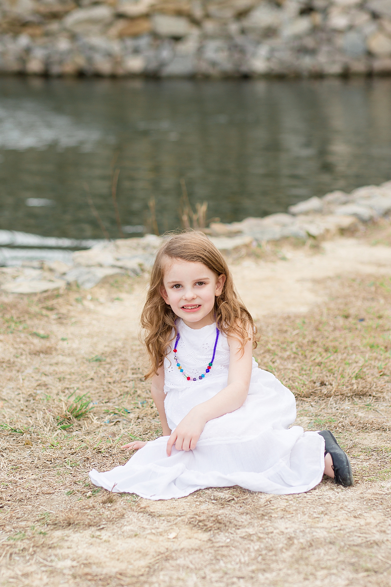 little girl sits in grass during springtime family photos in Dallas TX