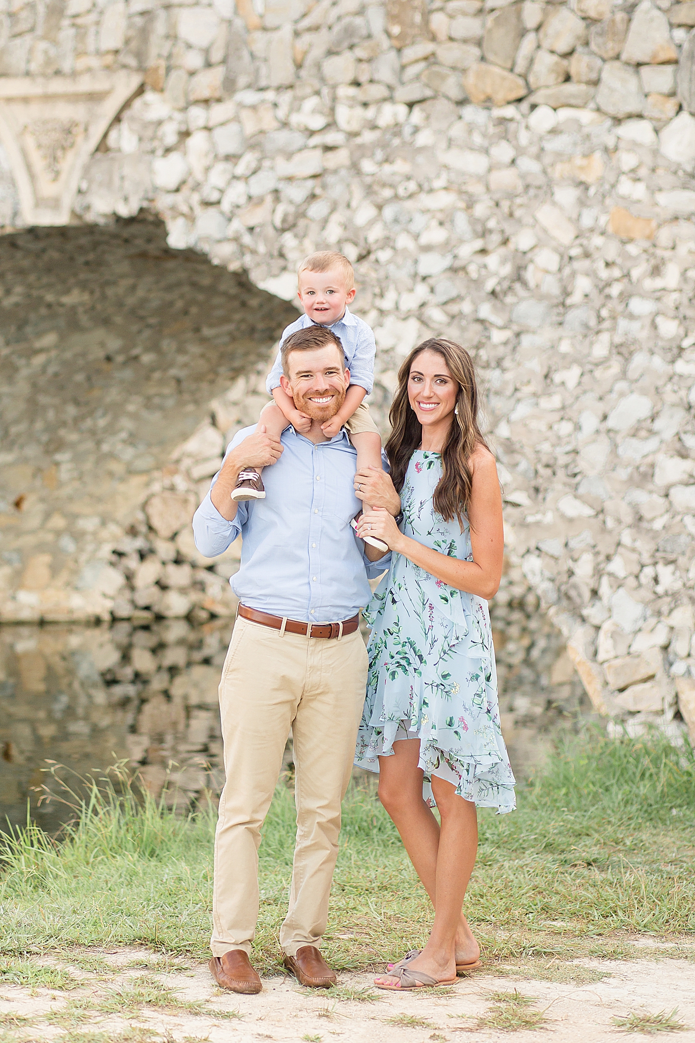 family of three poses by stone bridge in Adriatica Village