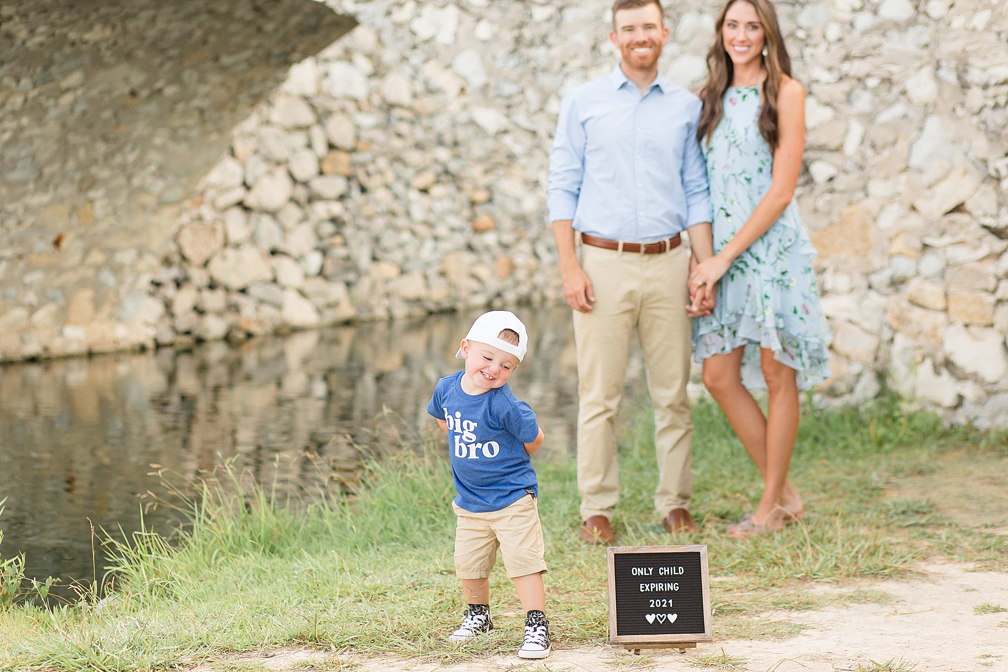 toddler poses by sign with pregnancy announcement captured by McKinney photographer Wisp + Willow Photography Co. 