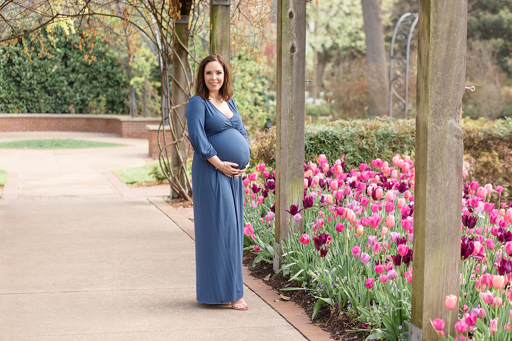 mom to be poses holding belly in blue dress for maternity photos