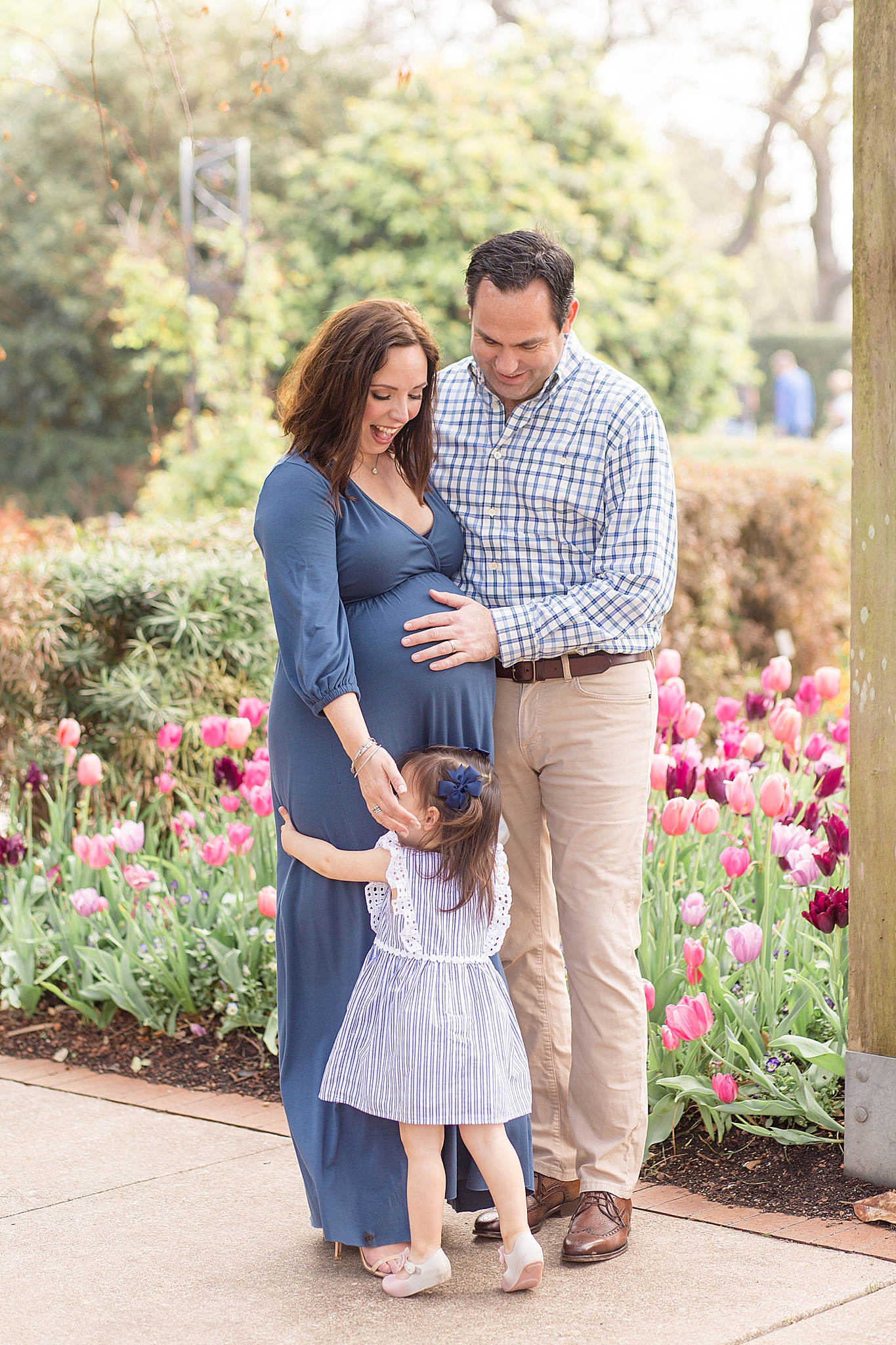 dad holds wife's belly during maternity photos in Dallas Arboretum