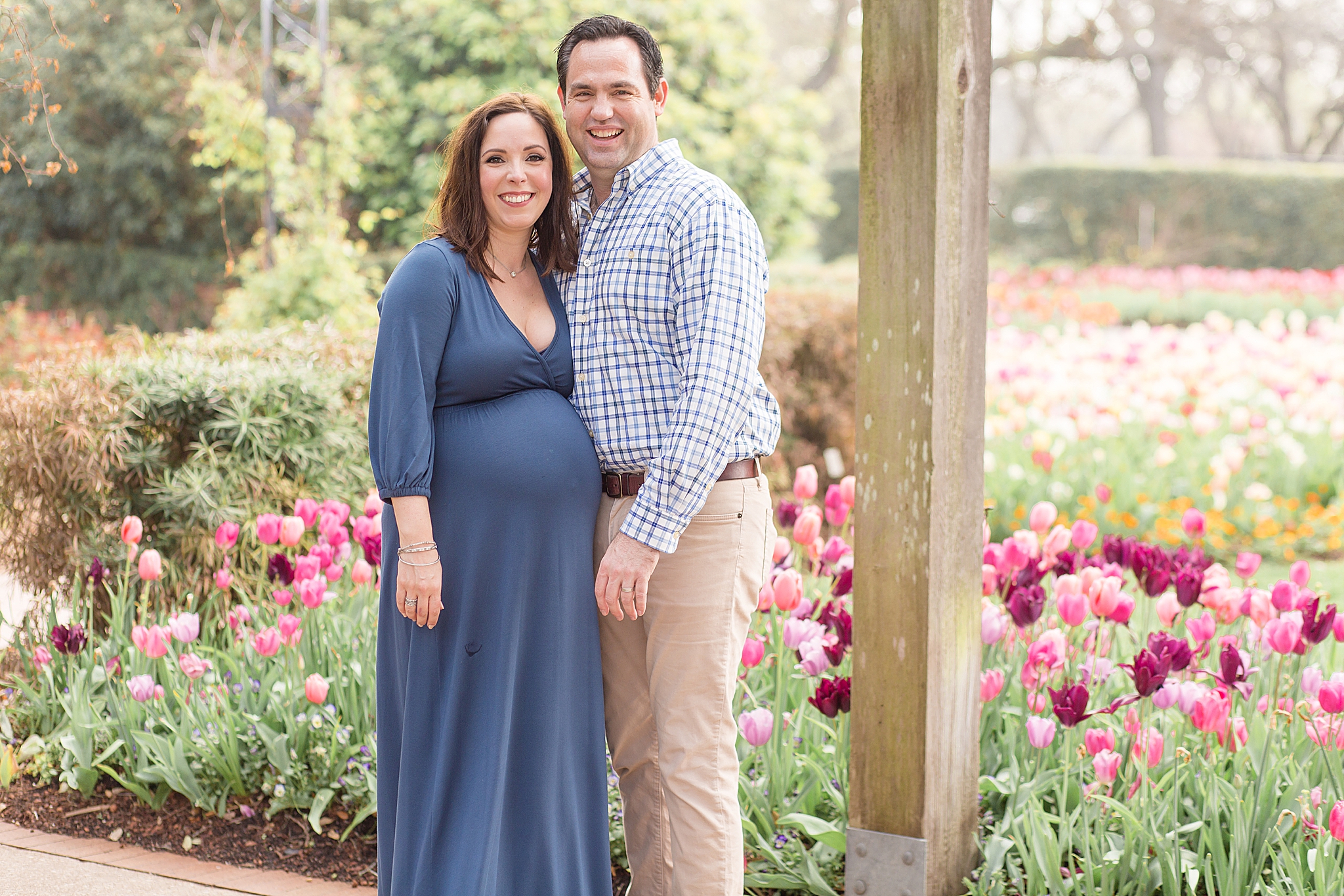 expecting parents pose by tulips in Dallas Arboretum