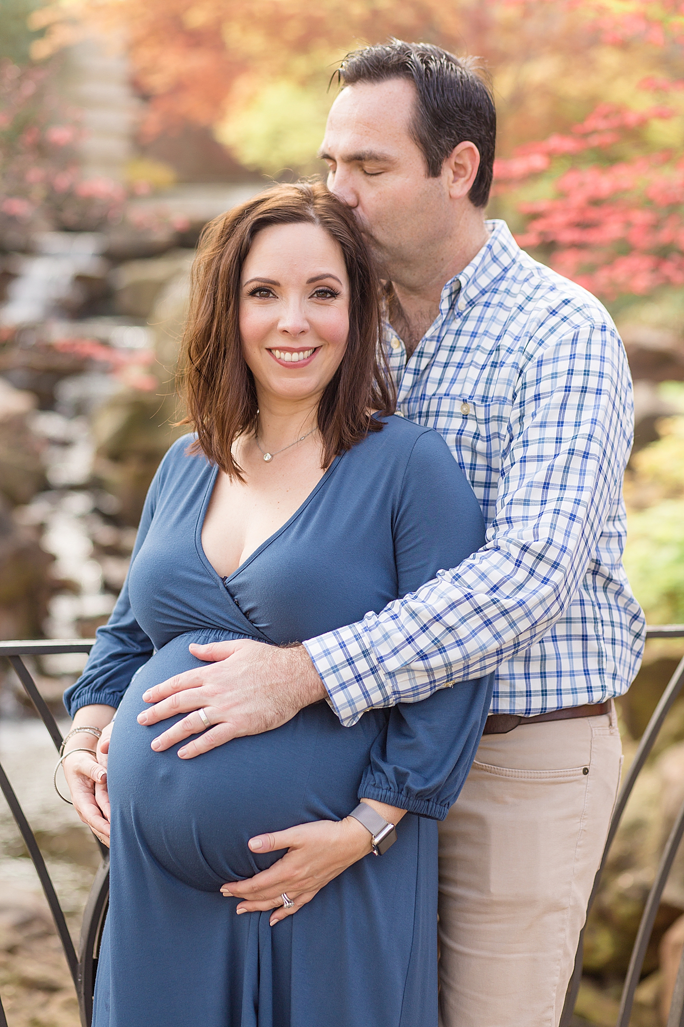 husband kisses wife's head during Dallas Arboretum maternity portraits 