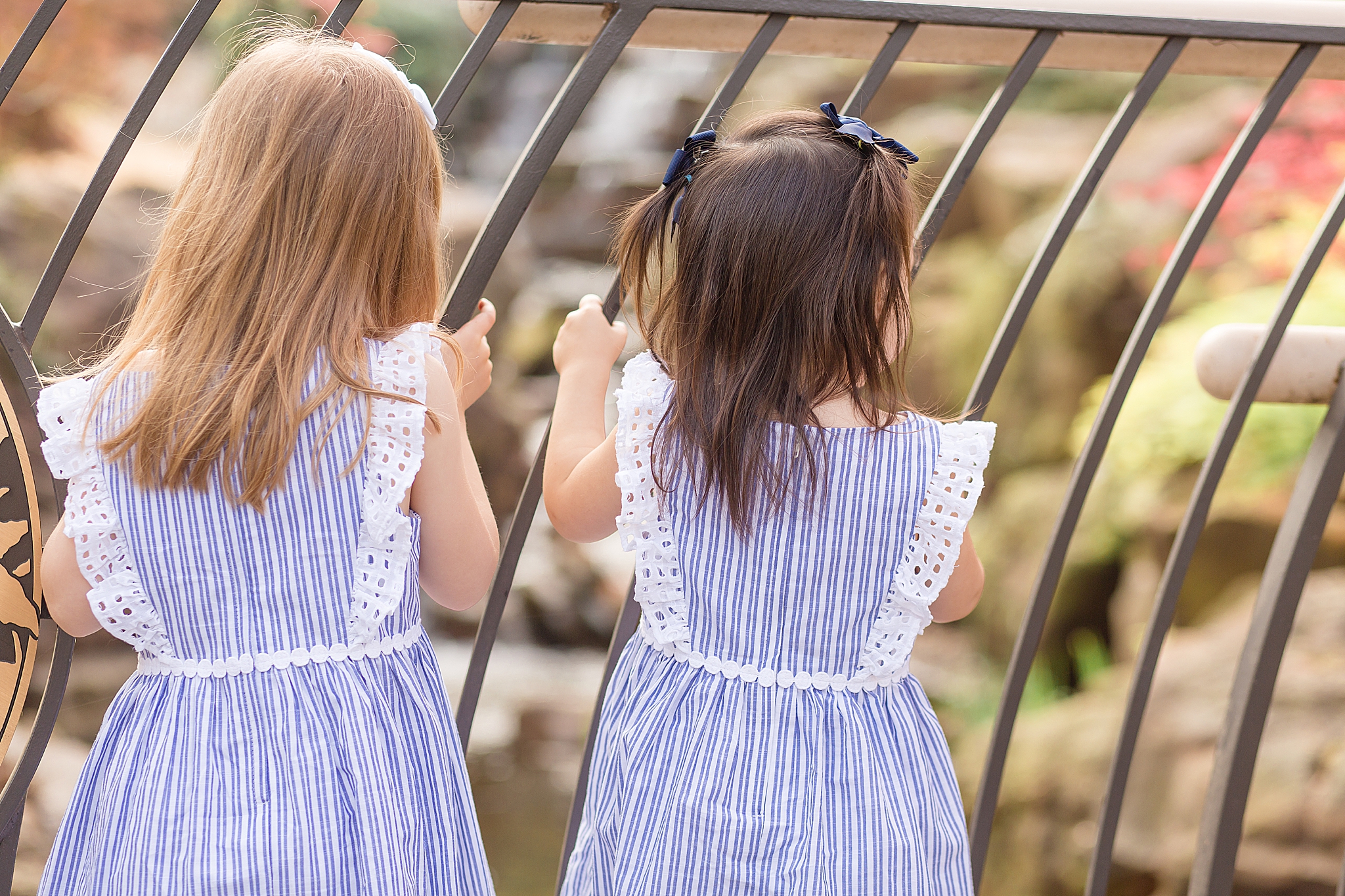 sisters in matching blue dresses look at waterfall in Dallas Arboretum