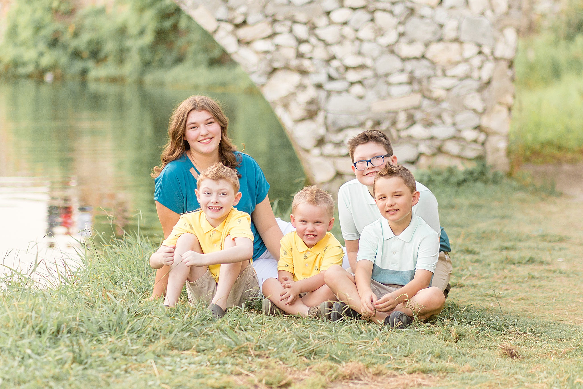 sister sits with four brothers by stone bridge in Adriatica Village