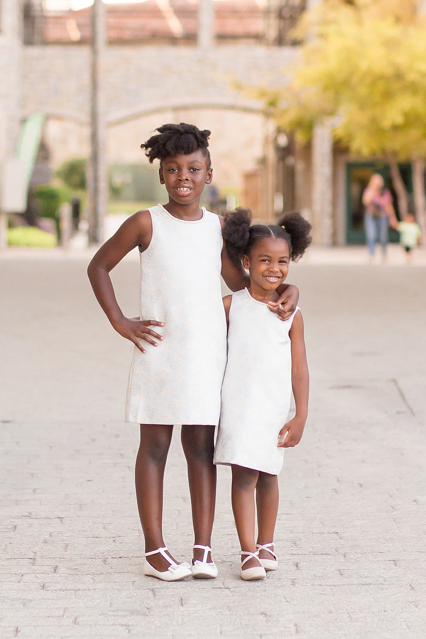 sisters in white sundresses hug during McKinney family portraits