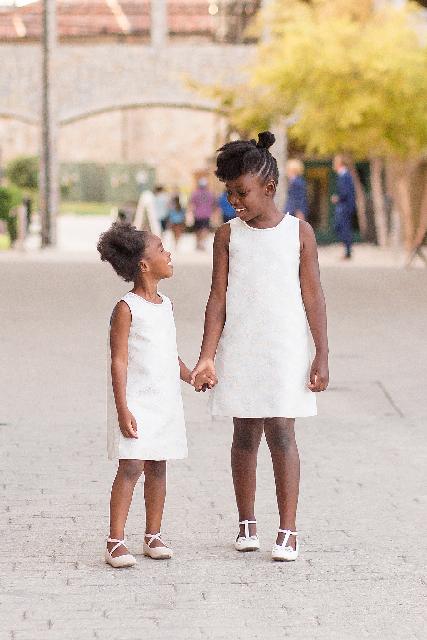 sisters in white dresses hold hands during McKinney family portraits