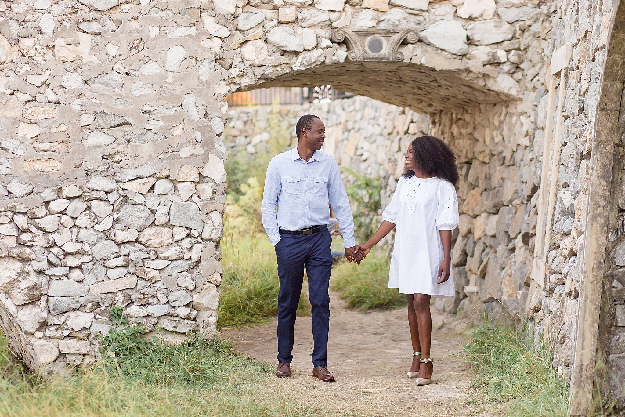 husband and wife walk through stone bridge at Adriatica Village during McKinney family portraits