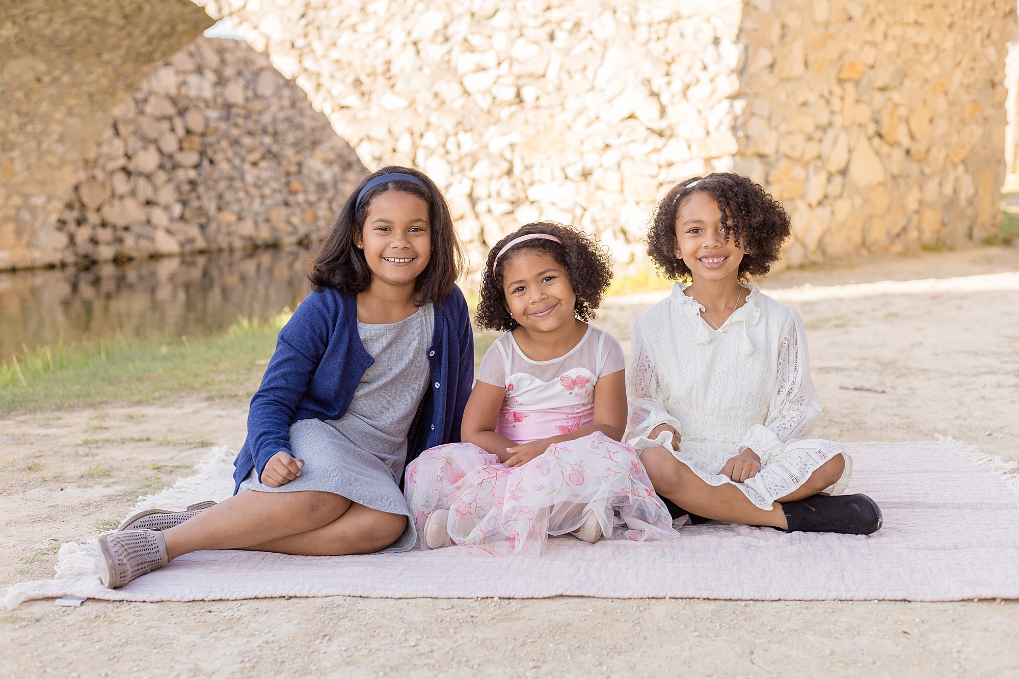 daughters pose under bridge at Bella Donna Chapel in McKinney, Texas for family portrait session 