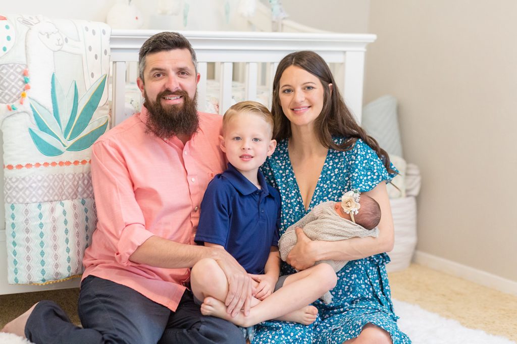 family of 4 poses in front of crib in nursery at their home during lifestyle newborn session with dallas newborn photographer Wisp + Willow Photography Co.