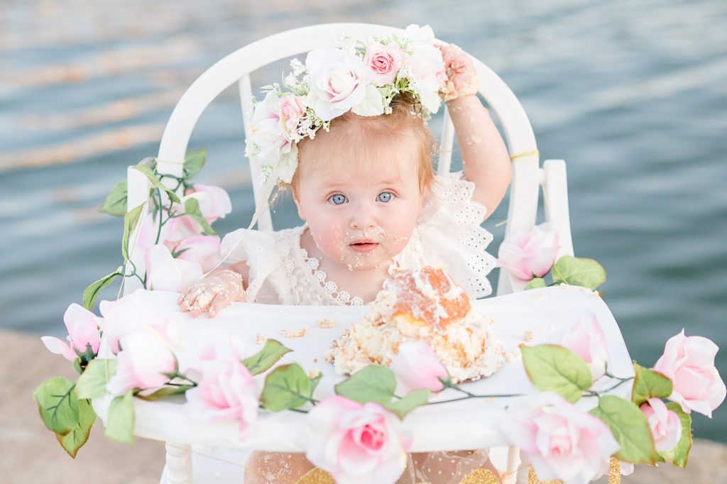 1 year old pulls on flower crown after her smash cake session with McKinney milestone photographer Wisp + Willow Photography Co. in McKinney TX at Adriatica Village