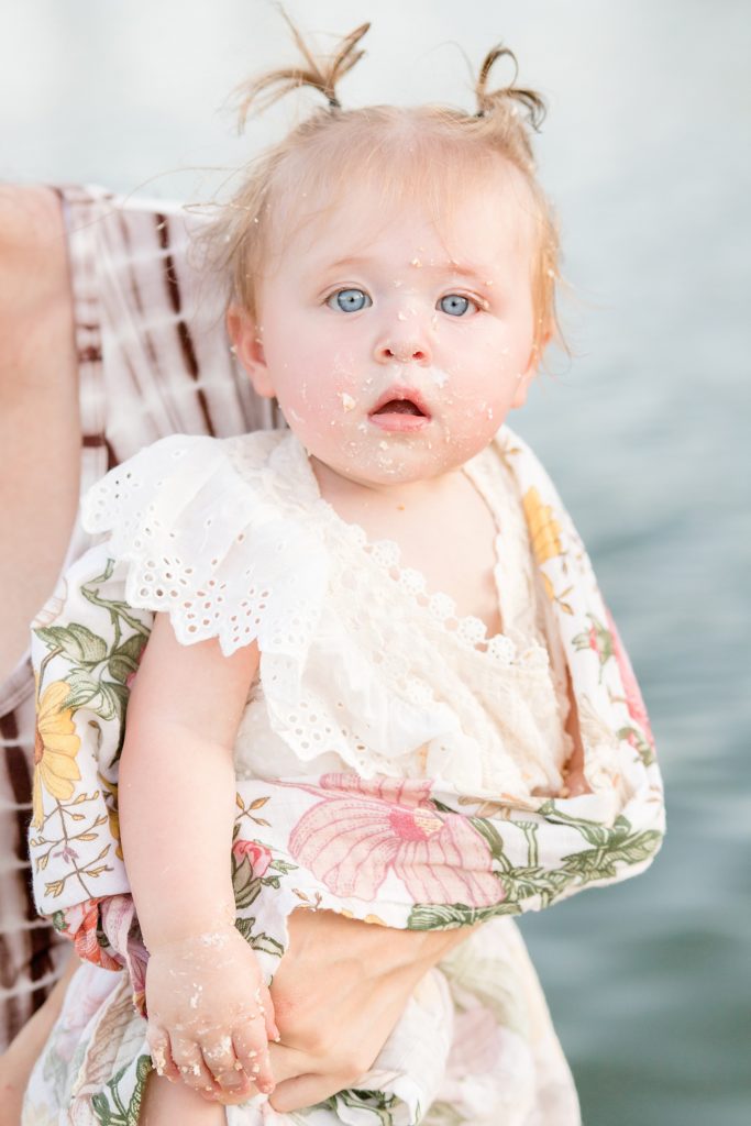 Mom holds baby girl after first birthday smash cake session with Wisp + Willow Photography Co.
