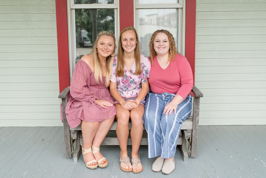 sisters sit on bench outside Frisco Heritage Museum for family portrait session with Wisp + Willow Photography Co. 