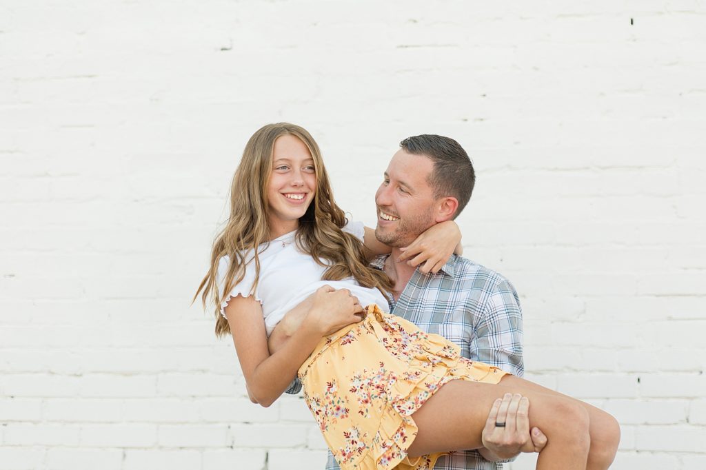 dad holds daughter during family portrait session in downtown mckinney square 