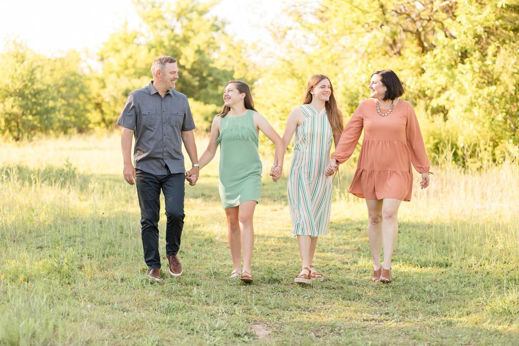family of four walks in field at frisco commons during family portrait session with Wisp + Willow Photography Co.