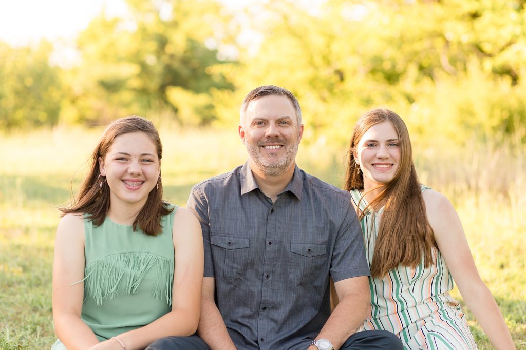 siblings pose in field together with dad during frisco family portrait session with family photographer wisp + willow photography co.