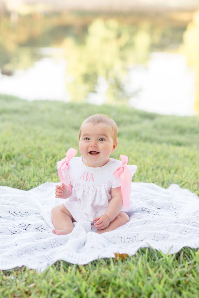 baby poses by lake for family portrait session 