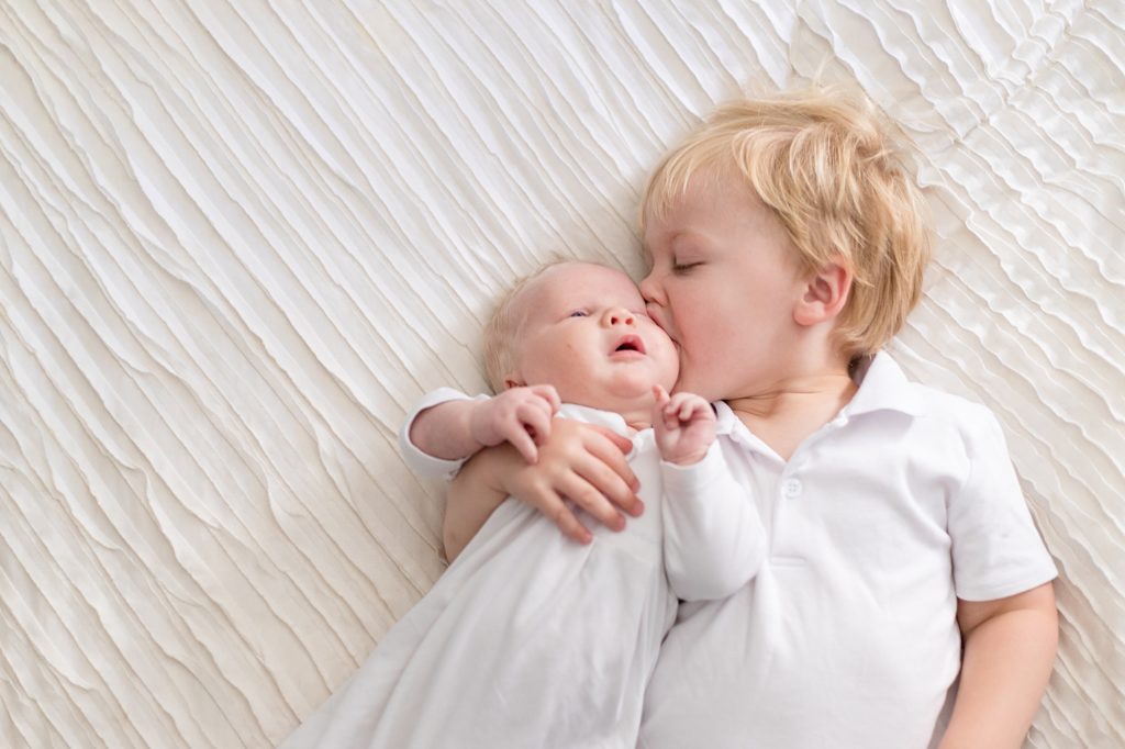 big brother kisses new baby brother during lifestyle newborn session with Wisp + Willow Photography Co.