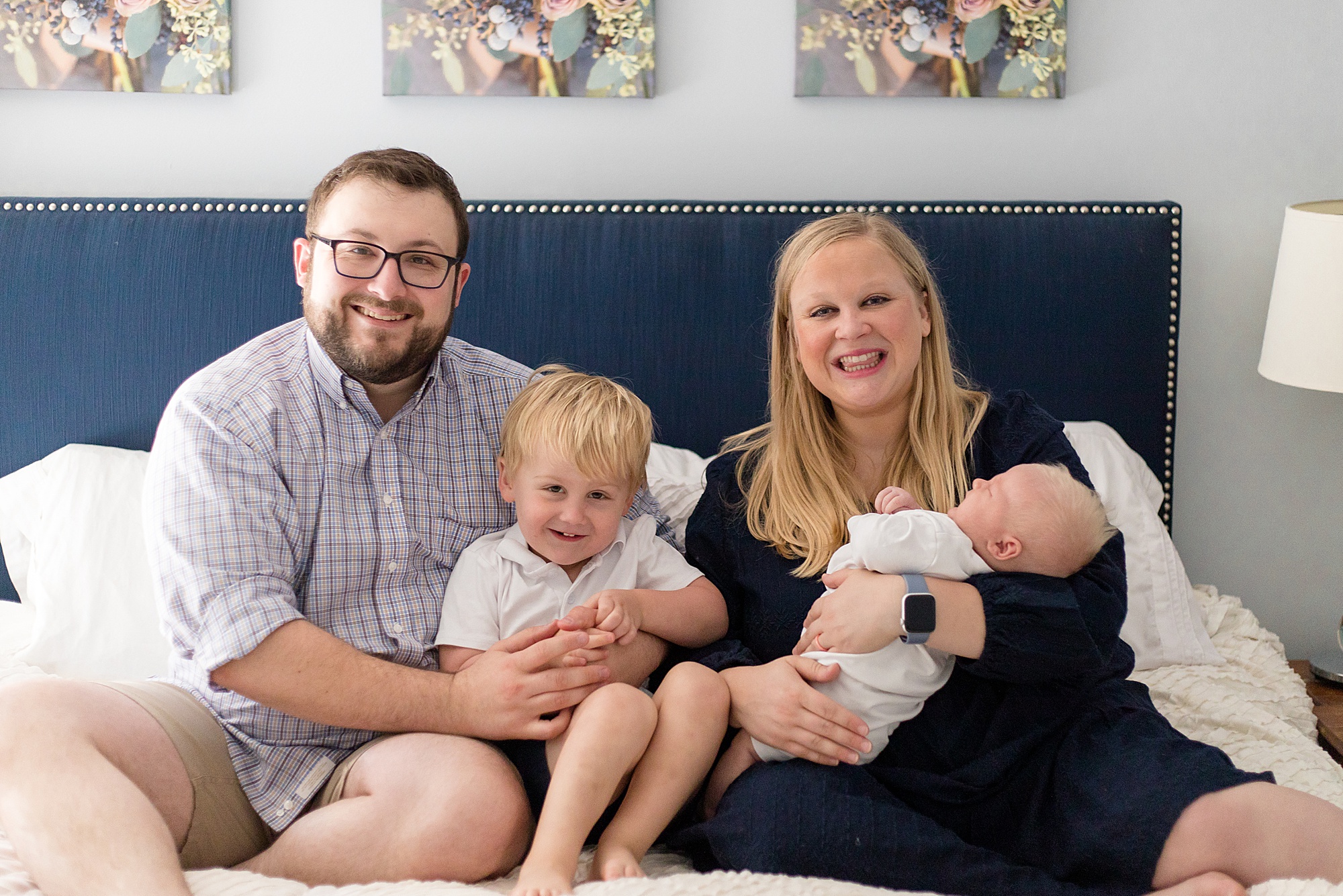 family poses on bed for lifestyle newborn session with Wisp + Willow Photography Co.