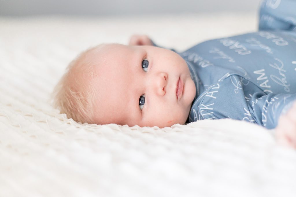 Baby boy lays on white blanket during lifestyle family session with Nashville family photographer Wisp + Willow Photography Co. 