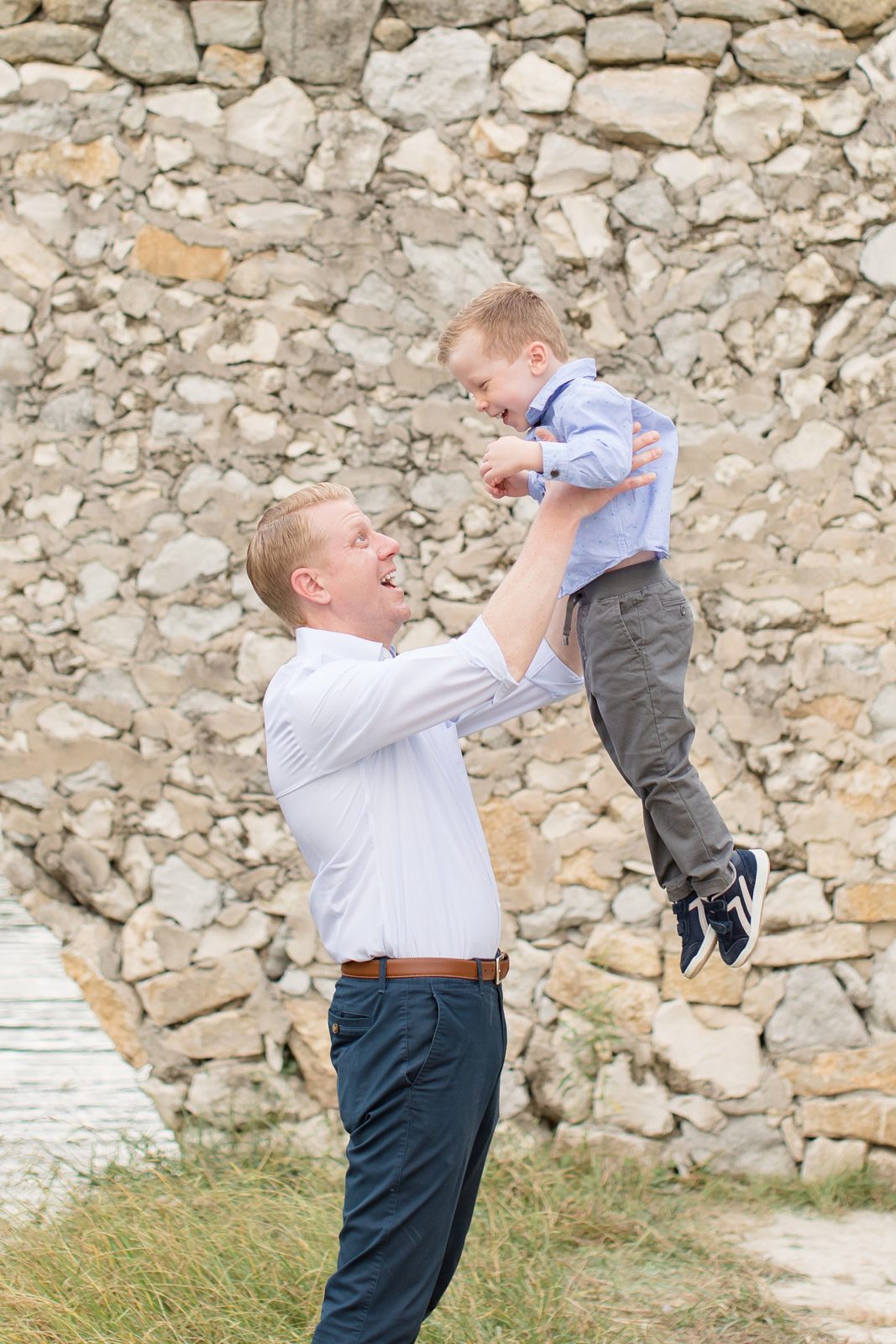 Dad throws son in the air during family session at Adriatica Village in McKinney, TX with family photographer Wisp + Willow Photography Co. 