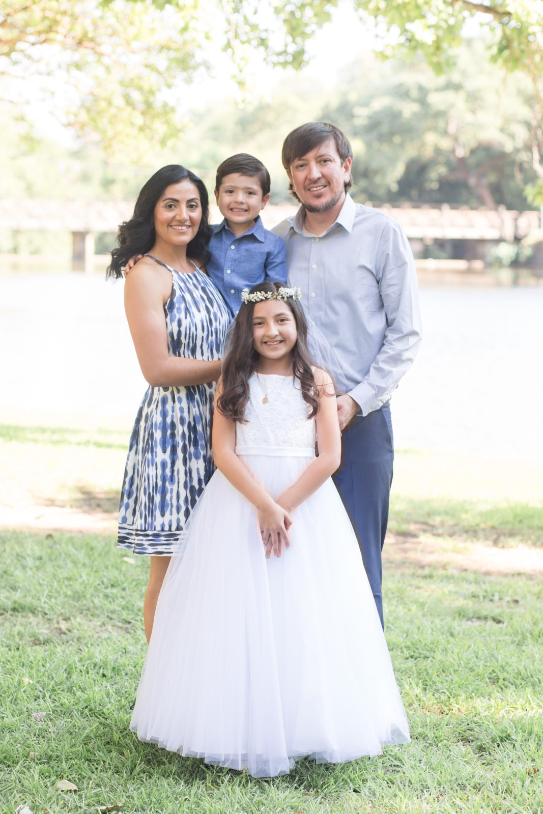 Family of 4 poses during family portraits in celebration of daughter's first communion at Lakeside park in Dallas, TX with Dallas event photographer 