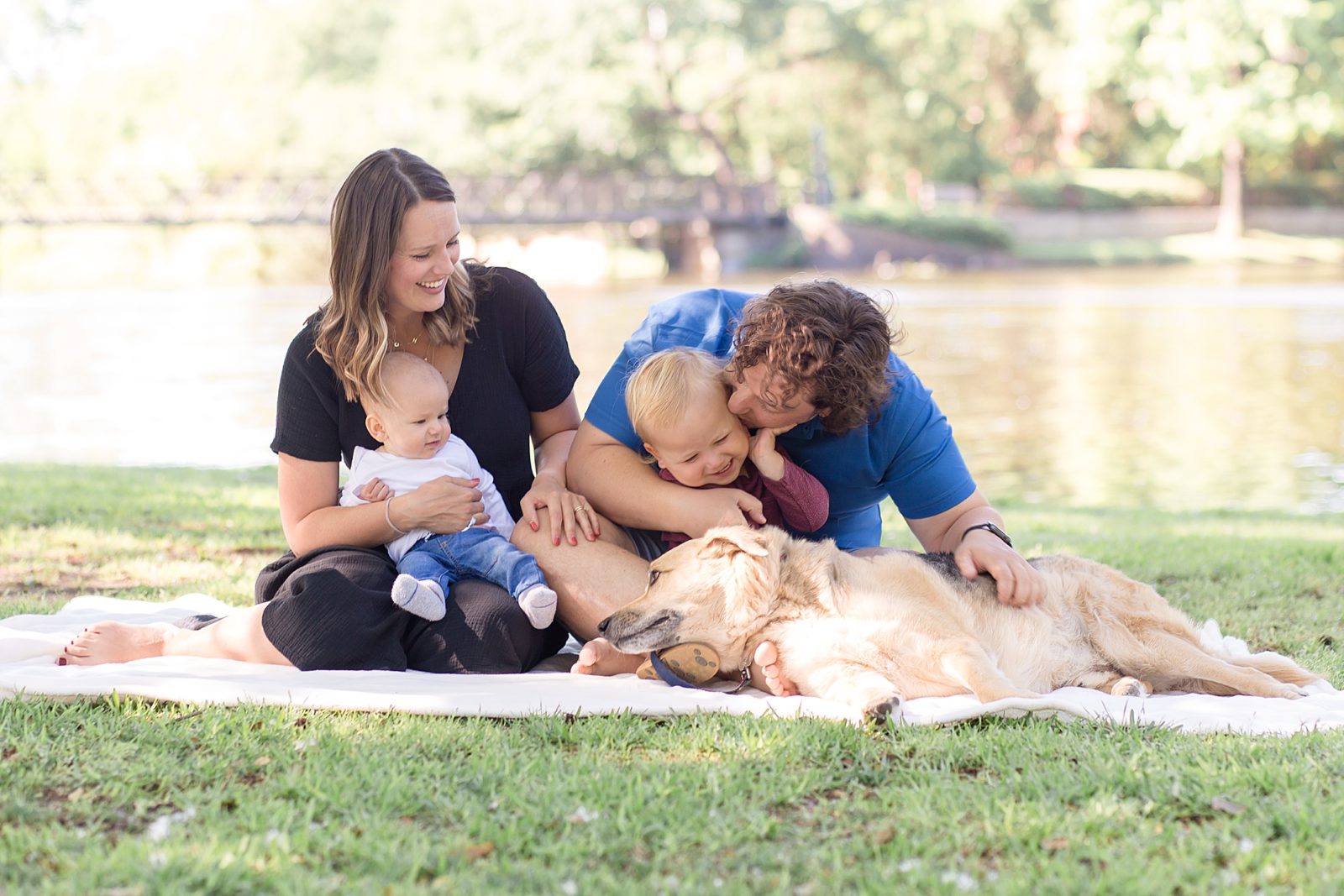 Family of four poses on blanket in front of pond during family portraits with Dallas portrait photographer Wisp + Willow Photography Co. 