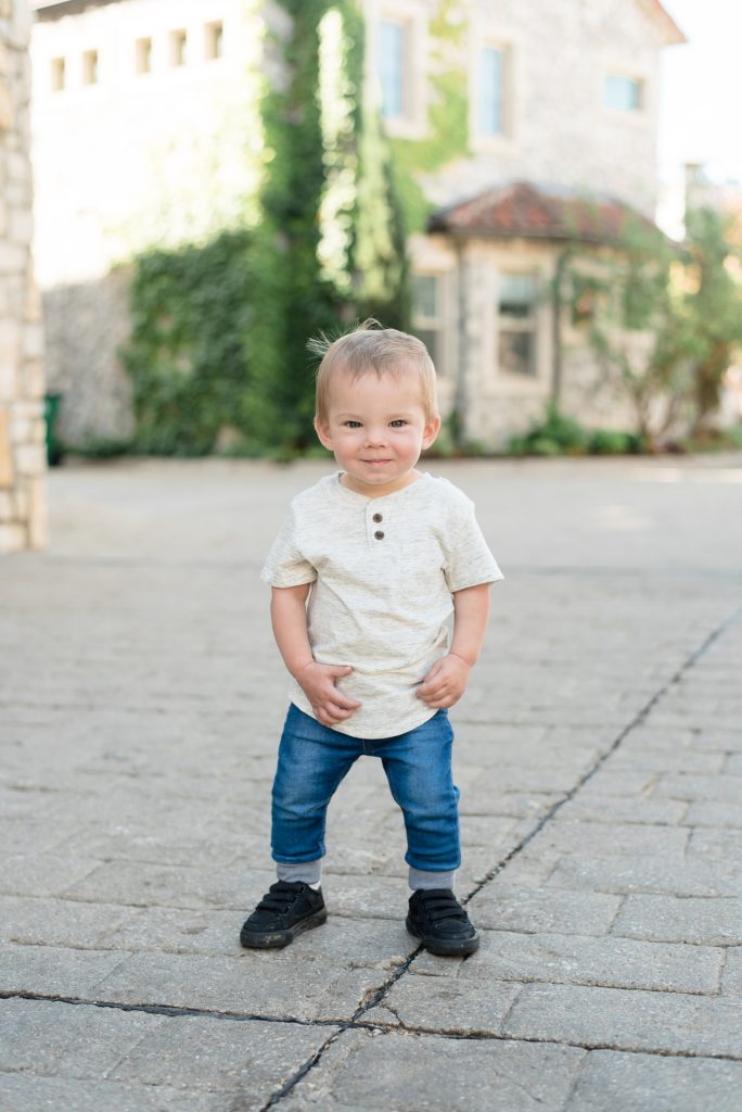 Little boy in tan button up stands on road during family portraits with Adriatica Village photographer Wisp + Willow Photography Co. 