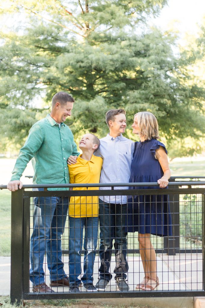 Family stands on bridge during fall mini session at Finch Park in McKinney, TX with family photographer Wisp + Willow Photography Co.