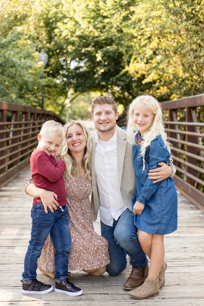 family poses on bridge for fall mini session at Pinkerton Park in Franklin, TN