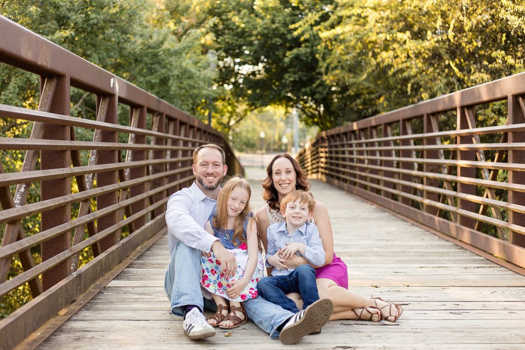 family sits on bridge at pinkerton park for fall mini session with family photographer Wisp + Willow Photography Co.