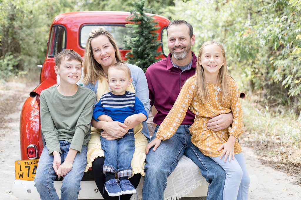 Family of 5 sits on bed of truck during Christmas red truck minis with Frisco family photographer Wisp + Willow Photography Co. 