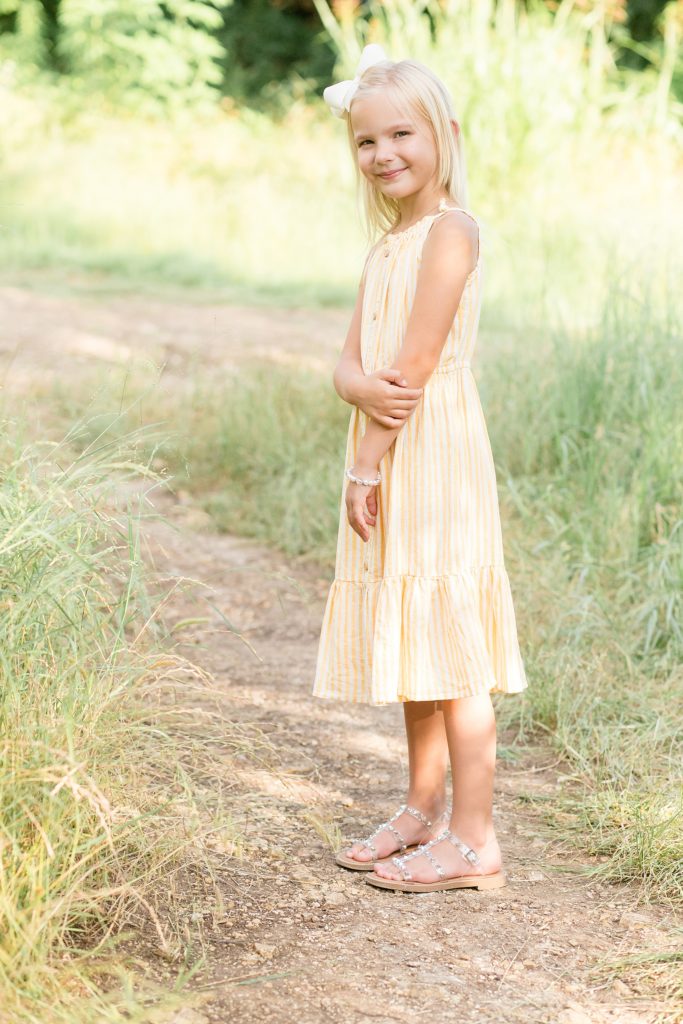 Little girl stands in tall grass at Arbor Hills Nature Preserve in the summer with Plano family photographer Wisp + Willow Photography Co. 