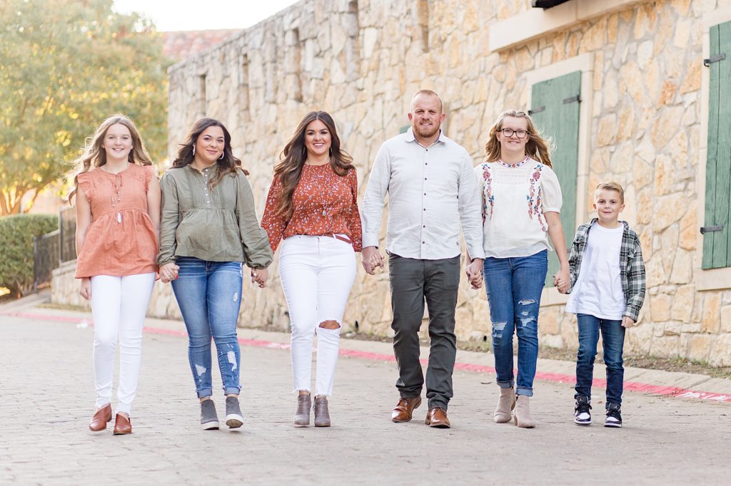 Family of 6 walks hand in hand down alley during family portrait session with McKinney family photographer Wisp + Willow Photography Co. 