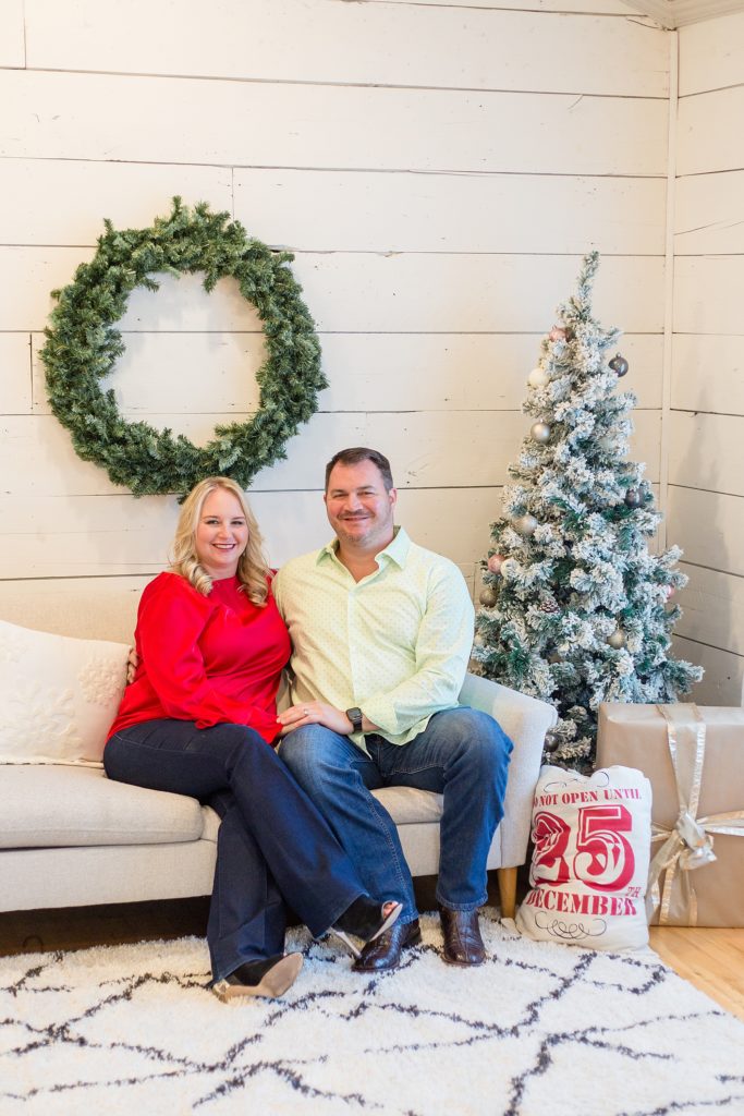 Couple poses on couch during Christmas session with McKinney mini sessions photographer Wisp + Willow Photography Co. 