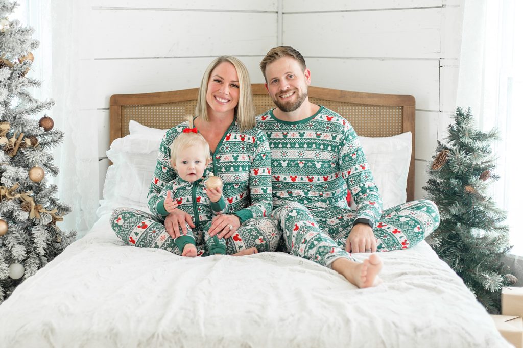 Family poses on bed in Christmas pajamas during family portrait session with McKinney mini sessions photographer Wisp + Willow Photography Co. 