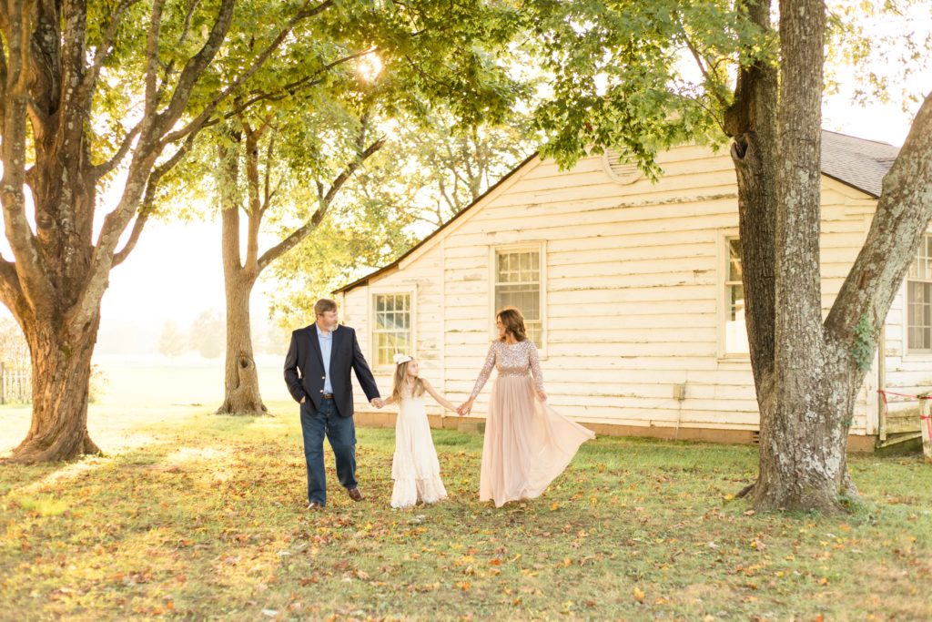 Family walks hand in hand in front of farm house at Harlinsdale Farm during family portrait session with Wisp + Willow Photography Co.