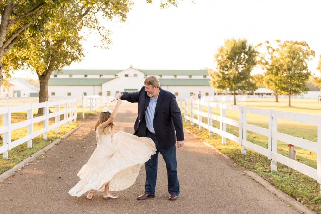 Dad twirls girl in peach gown in circles for creative shot during fall family portrait session with Wisp + Willow Photography Co. at Harlinsdale Farm in Franklin, TN.