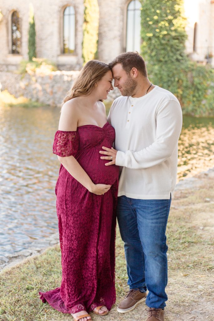 Husband holds wife's belly for maternity photo session at Adriatica Village in McKinney, TX with Wisp + Willow Photography Co.