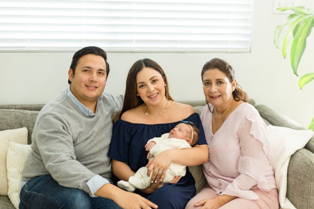 Family poses on couch in home during lifestyle newborn session with Dallas TX photographer Wisp + Willow Photography Co. 