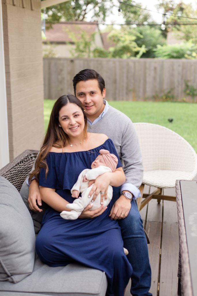 Family of 3 poses on patio with new baby girl during lifestyle newborn session with Dallas TX photographer Wisp + Willow Photography Co. 