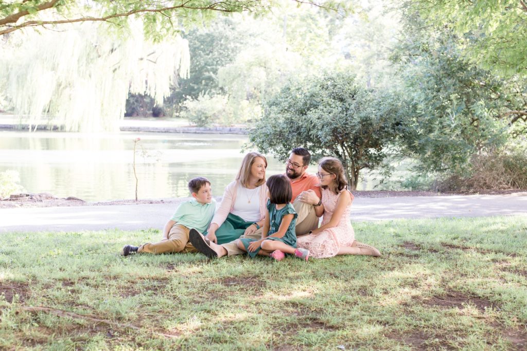 Family of 5 sits in front of pond at Centennial Park in Nashville, TN during family portrait session with Wisp + Willow Photography Co. Click to see more from this sweet family session on our blog! 