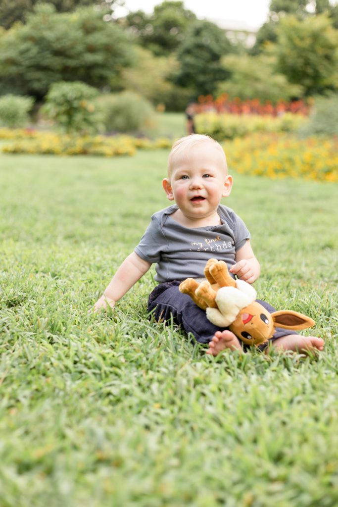 Baby boy holds stuffed animal in field in front of flowers at Centennial Park in Nashville, TN. Centennial Park is one of our favorite photo locations in Nashville. Click to read why we love it on our blog now! 