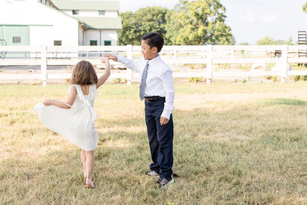 Siblings dance in field in front of Harlinsdale Farm in Franklin, TN during family portrait session with family photography team Wisp + Willow Photography Co. Click to read more about this photo session on our blog!
