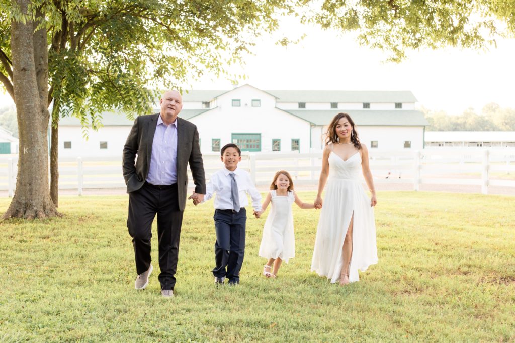 Family of four walks in grassy field in front of Harlinsdale Farm in Franklin, TN during family portrait session with Wisp + Willow Photography Co. Click to read more about this session on our blog!