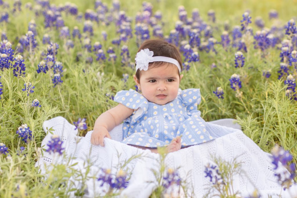 baby girl sits on blanket in field of bluebonnets in plano, tx during mommy and me portrait session with Wisp + Willow Photography Co. Click to see more from this sweet portrait session!