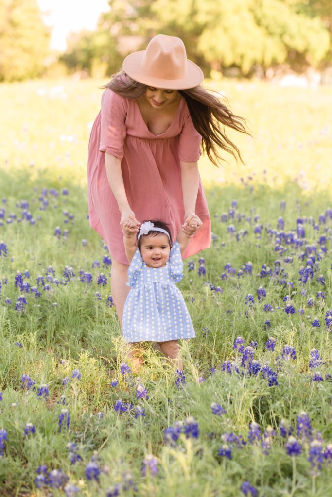 mom holds daughter up in field of bluebonnets during spring mommy and me session