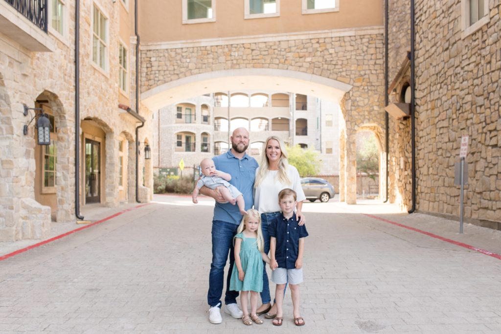 Family of 5 stands under awning at Adriatica Village in McKinney, TX during spring portrait session with family photography team Wisp + Willow Photography Co. Click to read more from this session on the blog!