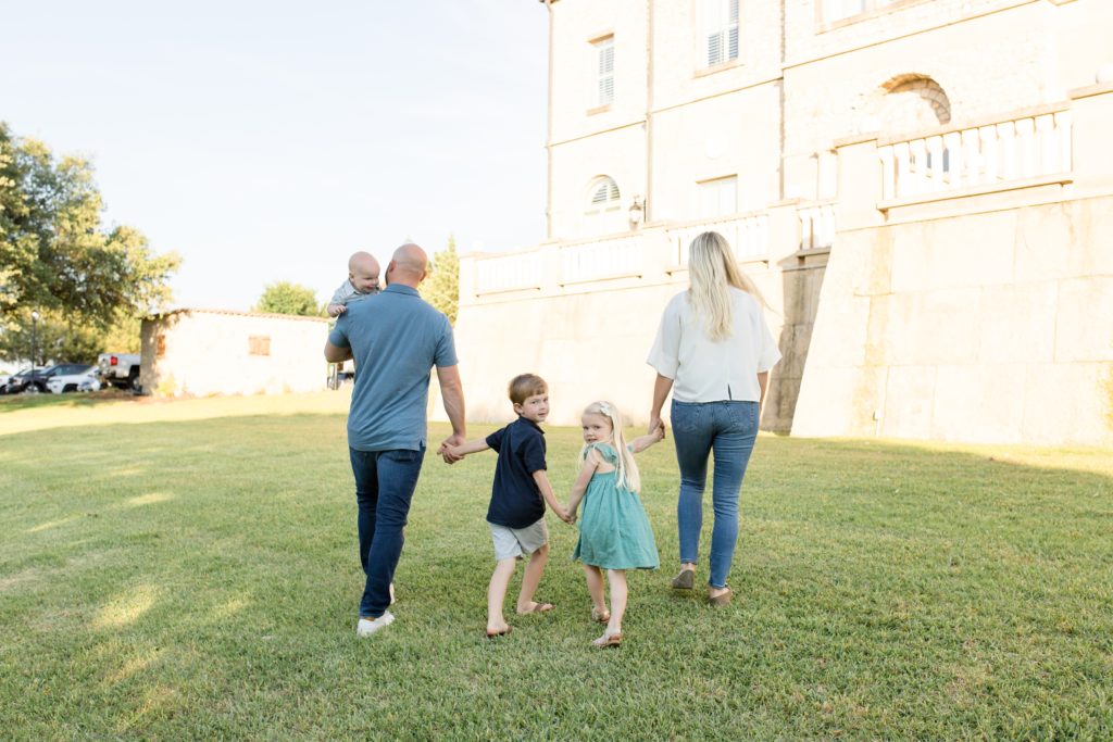 Family of 5 walks towards the water reservoir at Adriatica Village in McKinney, TX during portrait session with family photographer Wisp + Willow Photography Co. Click to see more from this sweet session live on the blog now!