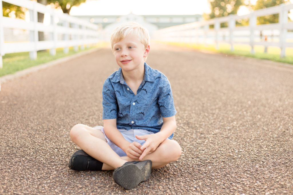 Boy in blue button up sits in gravel during spring mommy and me portrait session with family photography team Wisp + Willow Photography Co. Click to see more from this sweet session on our blog now!